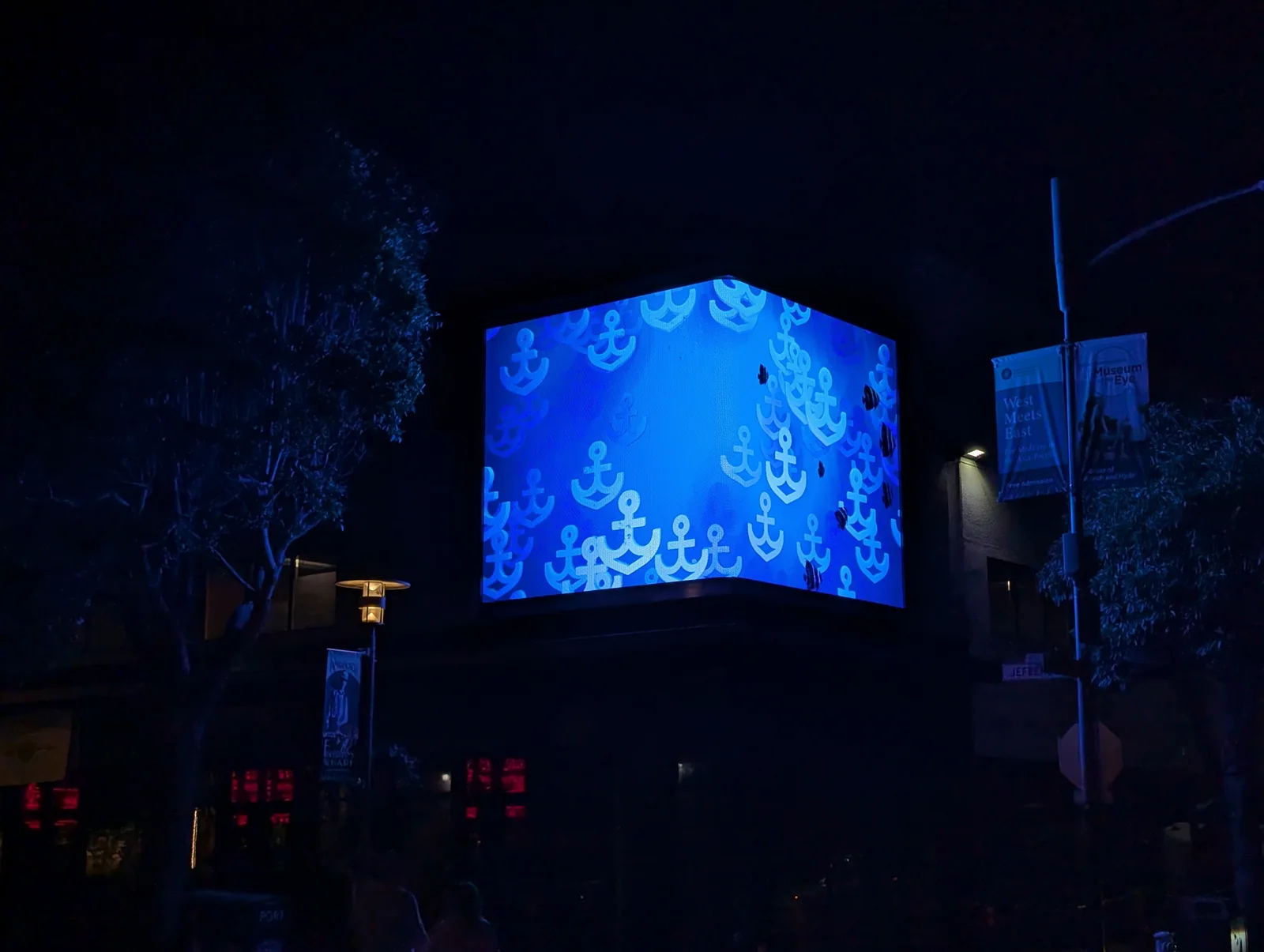 The corner LED volume after dark showing pale anchors drifting through deep blue water across both faces